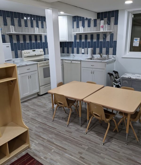 A clean and organized daycare room with various play stations.